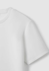 Camiseta blanca de manga corta con un escote redondo, textura suave y costuras limpias en las mangas y el dobladillo.