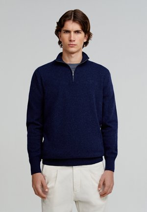 Navyblauer Wollpullover mit Viertelreißverschluss, strukturiertem Strick, gerippten Bündchen und Saum sowie einem silbernen Reißverschlussakzent.