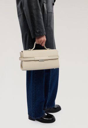 Béžová strukturovaná kabelka s horním uchem, s plochým designem a elegantním povrchem. Nositelná s dlouhým koženým kabátem a širokými džínami.