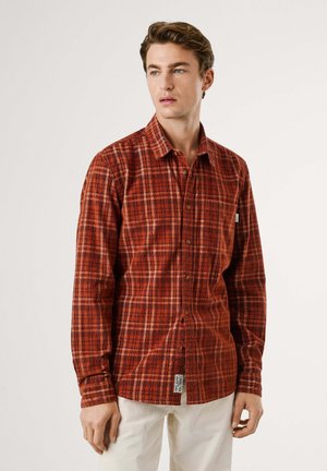 Camisa de cuadros en rojo y naranja de manga larga, hecha de algodón, que presenta un bolsillo, cuello abotonado y etiqueta en el dobladillo.