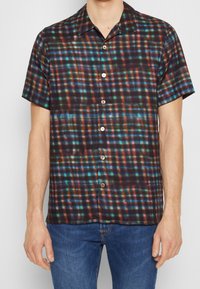 Camicia a maniche corte con bottoni in tessuto scuro, caratterizzata da un motivo a quadri multicolore con accenti blu, verdi e rossi. Texture liscia.