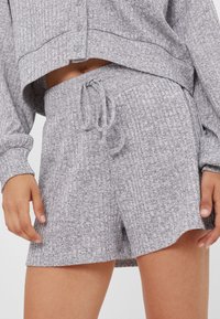 Gray textured shorts with a drawstring waist, featuring a breathable material and a slightly curved hem. Paired with a matching cropped top.