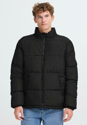 Veste rembourrée noire avec un col montant, fermeture éclair et poignets élastiques, dotée de sections matelassées et de poches latérales.