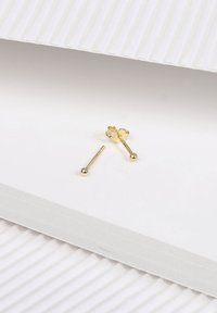 Gouden studoorbellen met een rechte stop en een bol accent. Het ontwerp heeft een gepolijste afwerking en rust op textuur oppervlaktes in wit.