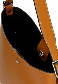 Borsa a tracolla in pelle tan con una superficie liscia, forma curva, tracolla regolabile e dettagli in argento lucido. Interno foderato in nero.