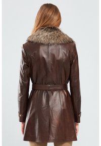 Brown leather coat with a faux fur collar, belted waist, and buttoned cuffs, featuring a fitted design and smooth texture.
