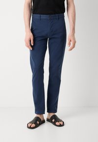 Chino navy blue din bumbac, cu un croi slim, talie standard cu închidere prin nasture și textură netedă. Design minimalist.