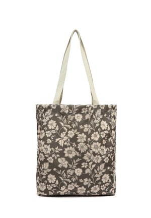 Bolso tote marrón con estampado floral blanco y asas largas de color crema, de pie sobre un fondo blanco.