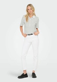 Polo shirt a righe con maniche corte in bianco e grigio, abbinato a pantaloni bianchi slim-fit e mocassini neri, accentuato da una cintura nera.