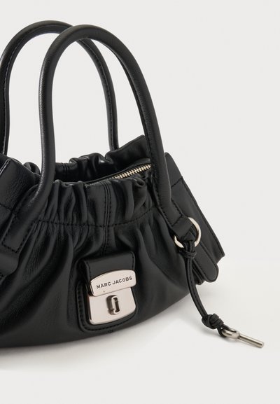 Petit sac à main en cuir noir avec des détails froncés, double poignée, fermeture argentée gravée « Marc Jacobs » et fermeture éclair latérale avec languette.