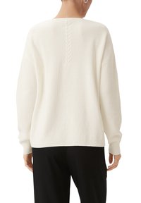 Weißer Strickpullover mit lockerer Passform, mit einer strukturierten Rückseite und Rippbündchen. Das Design umfasst ein Zopfmuster in der Mitte des Rückens.