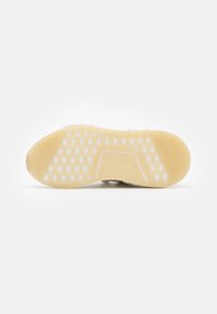 Semelle de chaussure avec un design en caoutchouc translucide texturé de couleur crème claire, présentant un motif de perforations hexagonales et un talon rond.