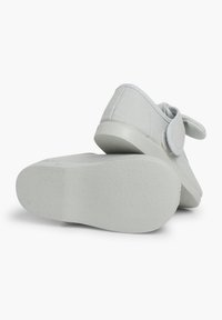Hellgraue Schuhe mit einem strukturierten Stoff-Obermaterial, Klettverschluss und einer glatten Gummisohle, die ein dezentes Muster und abgerundete Kanten aufweist.