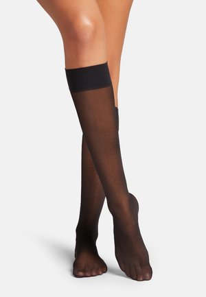 Svarta knästrumpor i hög längd med en genomskinlig, texturerad yta och mjukt band upptill. Öppen tå-design som visar fötterna.