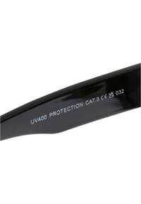 Ochelari de soare negri cu un finisaj lucios, având inscripția "UV400 PROTECTION CAT.3 CE UK 032" pe braț. Design elegant, curbat.