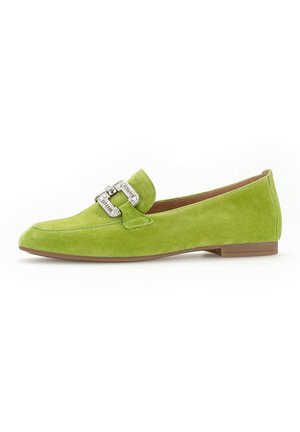 Grüne Wildleder-Slipper mit spitzem Zehenbereich, ausgestattet mit einer dekorativen, metallischen Schnalle und einer flachen, braunen Sohle. Glatte Textur über das gesamte Schuhwerk.