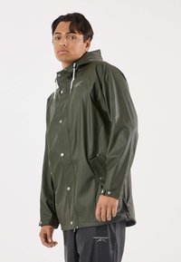 Groene waterdichte jas met capuchon, zilverkleurige drukknoopsluitingen, verstelbare manchetten en zijzakken. Gladde, glanzende textuur, modern ontwerp.