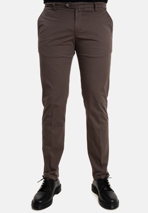 Pantaloni di cotone marroni con una vestibilità slim, dotati di tasche laterali e passanti per cintura, abbinati a scarpe nere stringate con suola spessa.
