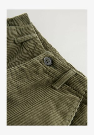 Tela de pana verde oliva con textura estriada, que presenta un botón negro circular y un detalle de trabilla.