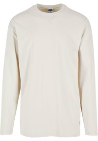Tricou crem cu maneci lungi din bumbac moale, cu decolteu rotund și slituri laterale pentru un plus de confort. Design minimalist, textură simplă.