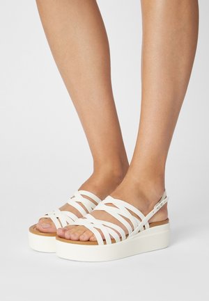 Sandali platform bianchi con più cinturini incrociati, materiale in gomma e base in legno. Cinturino posteriore regolabile per una vestibilità sicura.