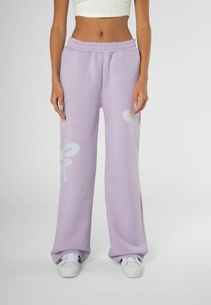 Pantalon de survêtement violet clair avec une jambe large, une taille élastique et une texture lisse, présentant un grand motif graphique blanc de chaque côté.
