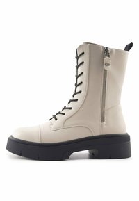 Botín de cuero color beige con cordones negros, cierre lateral con cremallera, suela texturizada y una plataforma gruesa negra. Presenta una punta redondeada.