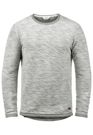 Pull en maille gris clair avec un motif texturé, encolure ronde et manches longues. Présente une petite étiquette en cuir marron en bas de l'ourlet.