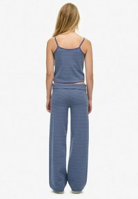 Gestreepte blauwe pyjama-set met een aansluitende crop top en loszittende broek, gemaakt van zachte stof en voorzien van een elastische tailleband voor comfort.