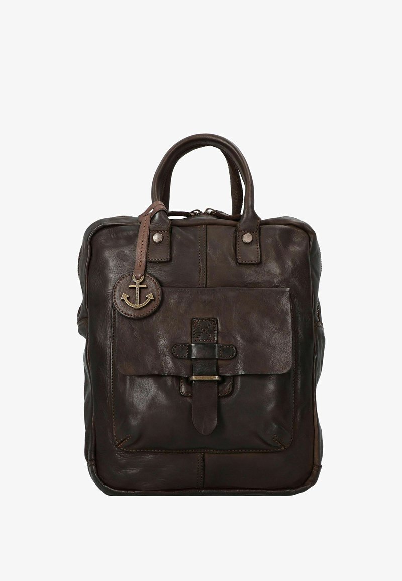 Mochila de cuero marrón con dos asas superiores, un bolsillo frontal con solapa asegurado por una correa, detalles metálicos y un charm con forma de ancla. Acabado texturizado.