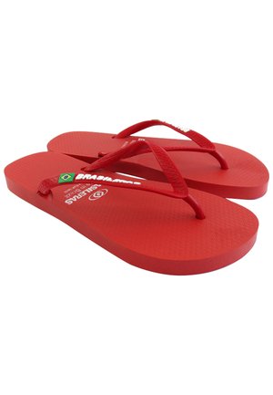 Chanclas rojas de goma con plantilla texturizada, tiras delgadas y detalles de logo. Suela plana con bordes redondeados y emblema de la bandera brasileña.