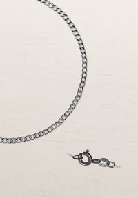 Silver metal chain necklace, featuring interlocking links, a smooth texture, and a round clasp with engraved detailing for secure closure.