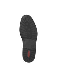 Suola di scarpa in gomma nera con design del battistrada texture, dotata di un pad circolare centrale e un'etichetta di marca rossa.