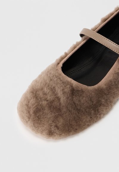 Ballet flat marrone peloso con punta arrotondata e una sottile cinghia. Tessuto morbido con un interno nero liscio e design minimalista.