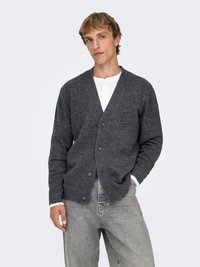 Gray wool cardigan with a v-neck and front buttons. Features ribbed cuffs and hem, worn over a white henley shirt and gray jeans.