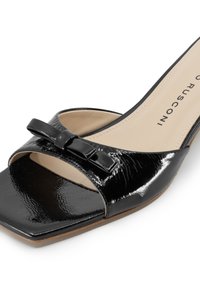 Sandalo a scivolo in vernice nera con punta aperta, ampia fascia e finitura testurizzata, dotato di un dettaglio a fiocco nella parte superiore.