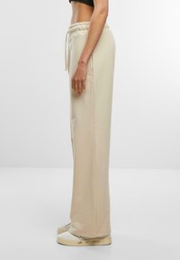 Beige Sweatpants mit relaxed Fit, elastischem Bund und Kordelzug. Glattes Material mit Seitentaschen und geradem Bein-Design.