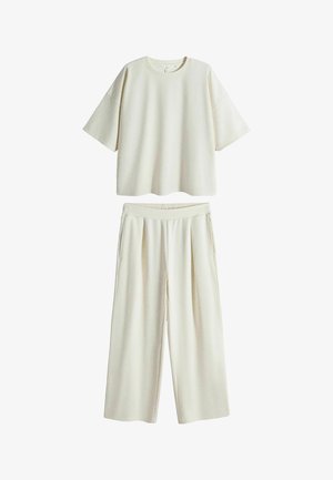 Roomkleurige losse top met korte mouwen, gecombineerd met hoog getailleerde wijde broeken met een elastische tailleband en zijzakken.