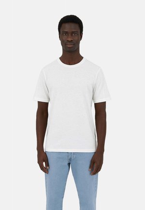 Weißes Baumwoll-T-Shirt mit kurzen Ärmeln und Rundhalsausschnitt, kombiniert mit hellblauen Jeans. Schlichtes Design, keine Muster oder Logos.