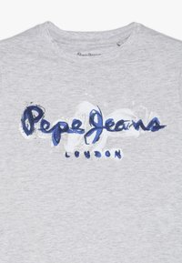 Szary bawełniany t-shirt z dużym niebiesko-białym nadrukiem logo z napisem „Pepe Jeans London” w stylizowanej czcionce.