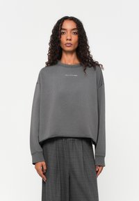 Grijze sweatshirt met een ontspannen pasvorm, ribbelkraag en verlaagde schoudernaden. Bevat een klein logo op de borst.