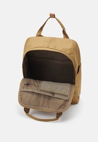 Καφέ υφασμάτινος σακίδιο με χερούλι, που διαθέτει ευρύχωρο εσωτερικό και μπροστινή τσέπη με πλέγμα και κλείσιμο με φερμουάρ.