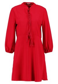 Červené šaty s mandarinovým límcem, dlouhými volánovými rukávy a zavazováním se třásněmi. Hladká tkanina s přiléhavým živůtkem a rozšířenou sukní.