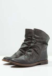 Bottes chelsea décontractées en cuir gris foncé avec une finition texturée et une semelle plate. Présente un matériau froncé autour de la cheville.