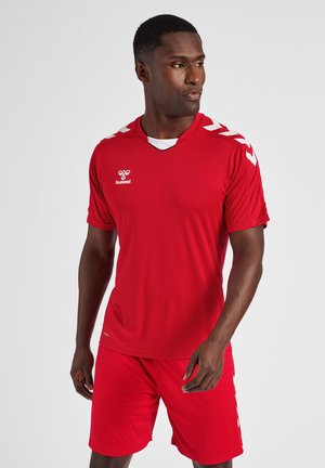 Rode sporttshirt en shortset gemaakt van ademend materiaal. T-shirt heeft witte accenten op de schouders en het logo, met een V-hals ontwerp.