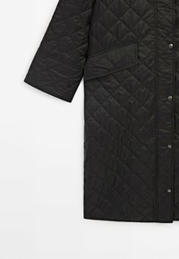 Zwarte gewatteerde jas met drukknopen, met een diamantpatroon, ronde halslijn en een zijzak. Gladde, glanzende textuur.