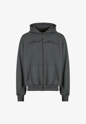 Sivý zipsový hoodie s prednou klokankovou vreckom, kapucňou so sťahovacou šnúrkou a čiernym vyšitým logom naprieč hrudníkom. Jemná textúra, priliehavé manžety.