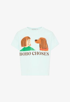 Chemise bleu clair à manches courtes avec un dessin animé d'une personne faisant face à un chien, texte « BOBO CHOSES » sous l'illustration.
