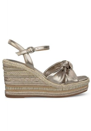 Sandali wedge in bronzo metallico con design anteriore annodato, cinturino alla caviglia regolabile e dettagli sulla base intrecciati e testurizzati. Leggeri e con punta aperta.