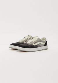 Sneakers featuring a combination of black, grey, and cream suede, with a textured upper, white laces, and a rubber sole.